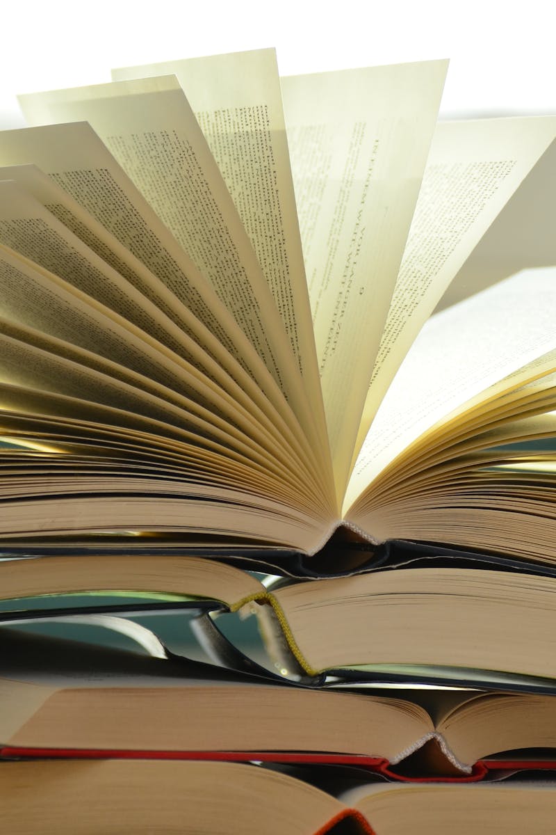 A close-up of a stack of open books with pages fanned out, capturing a study atmosphere.