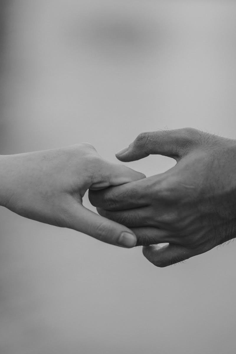 Monochrome image of two hands holding, symbolizing love and connection.