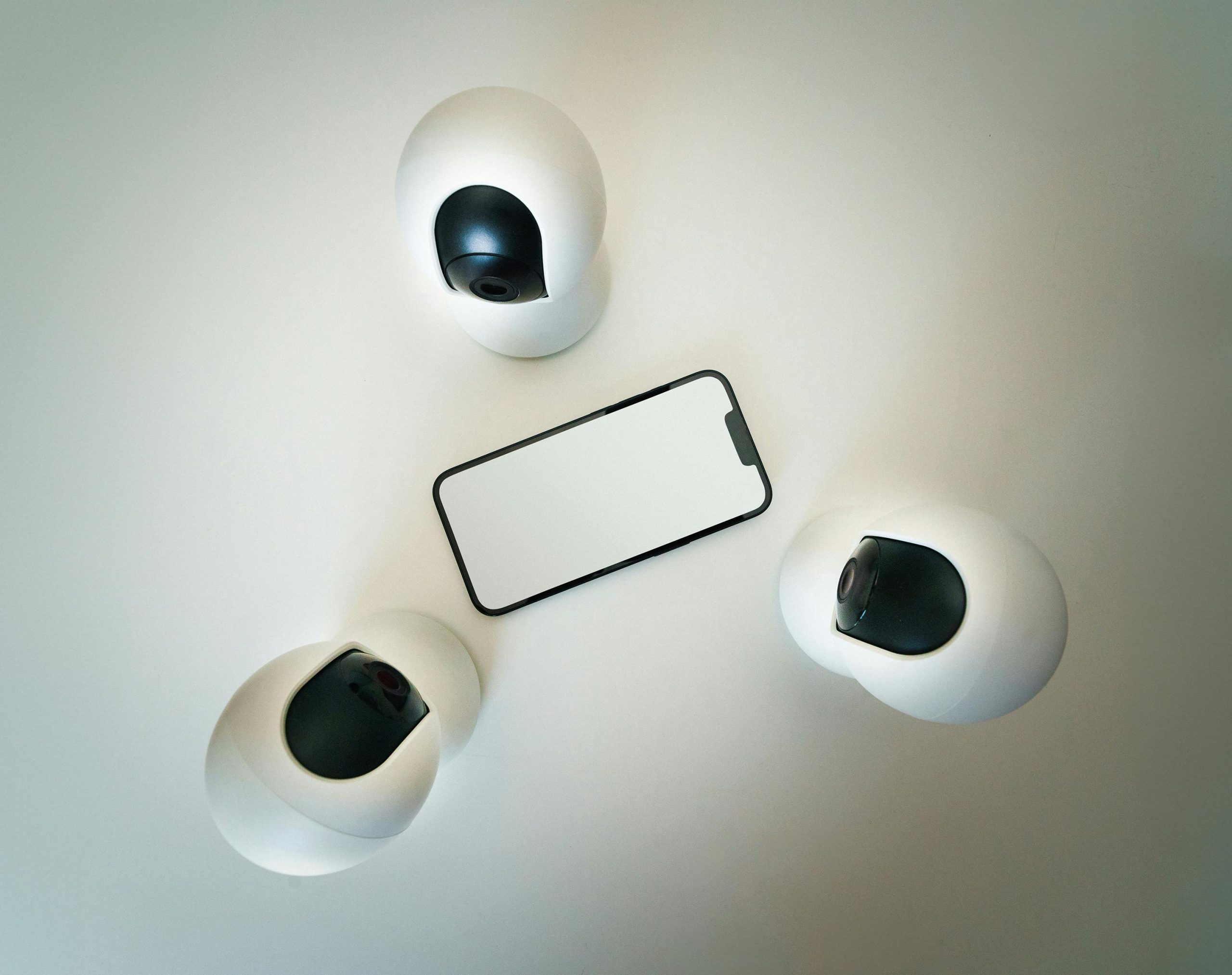 Smartphone surrounded by security cameras on a modern, minimalist setup.