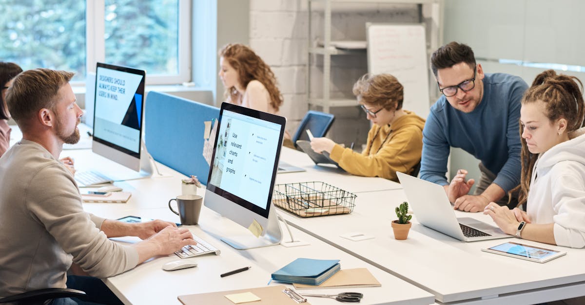 Team collaboration in a modern office setting with computers and diverse employees working together.