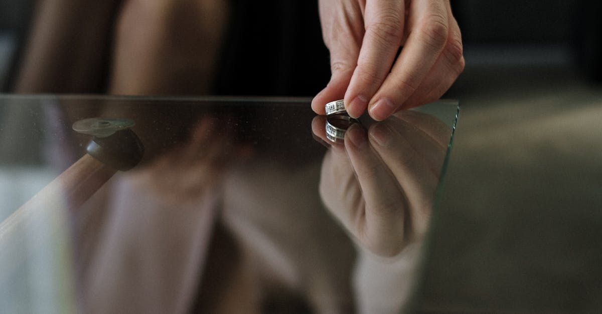 A person placing a wedding ring on a glass table, symbolizing separation or divorce.