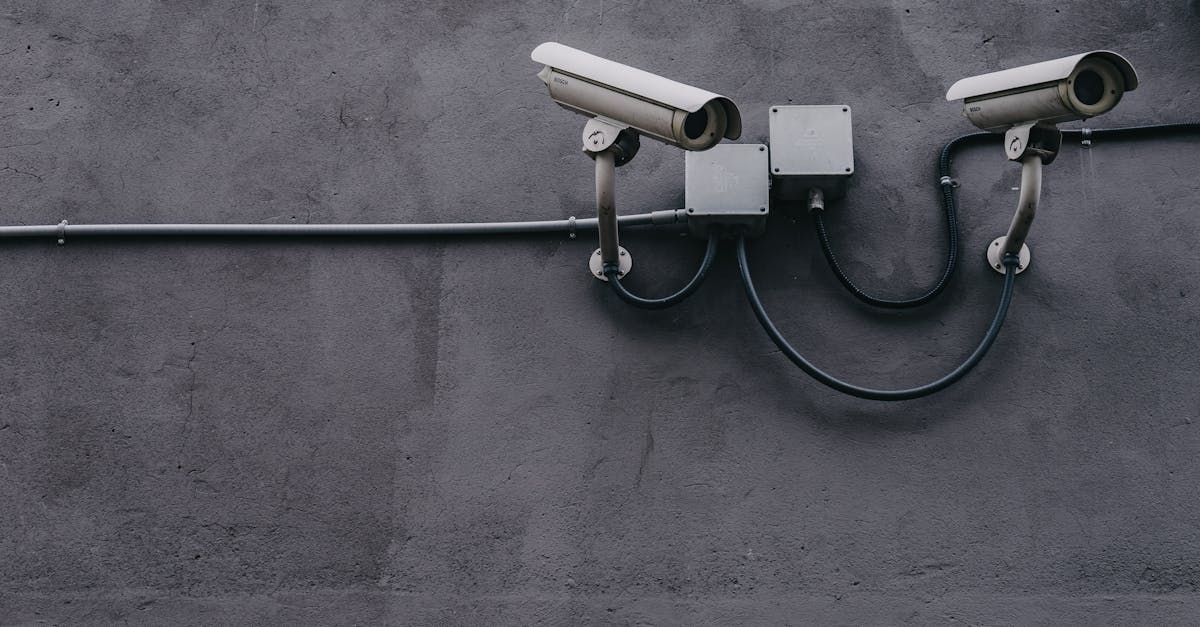 Two surveillance cameras mounted on a concrete wall, highlighting security technology.