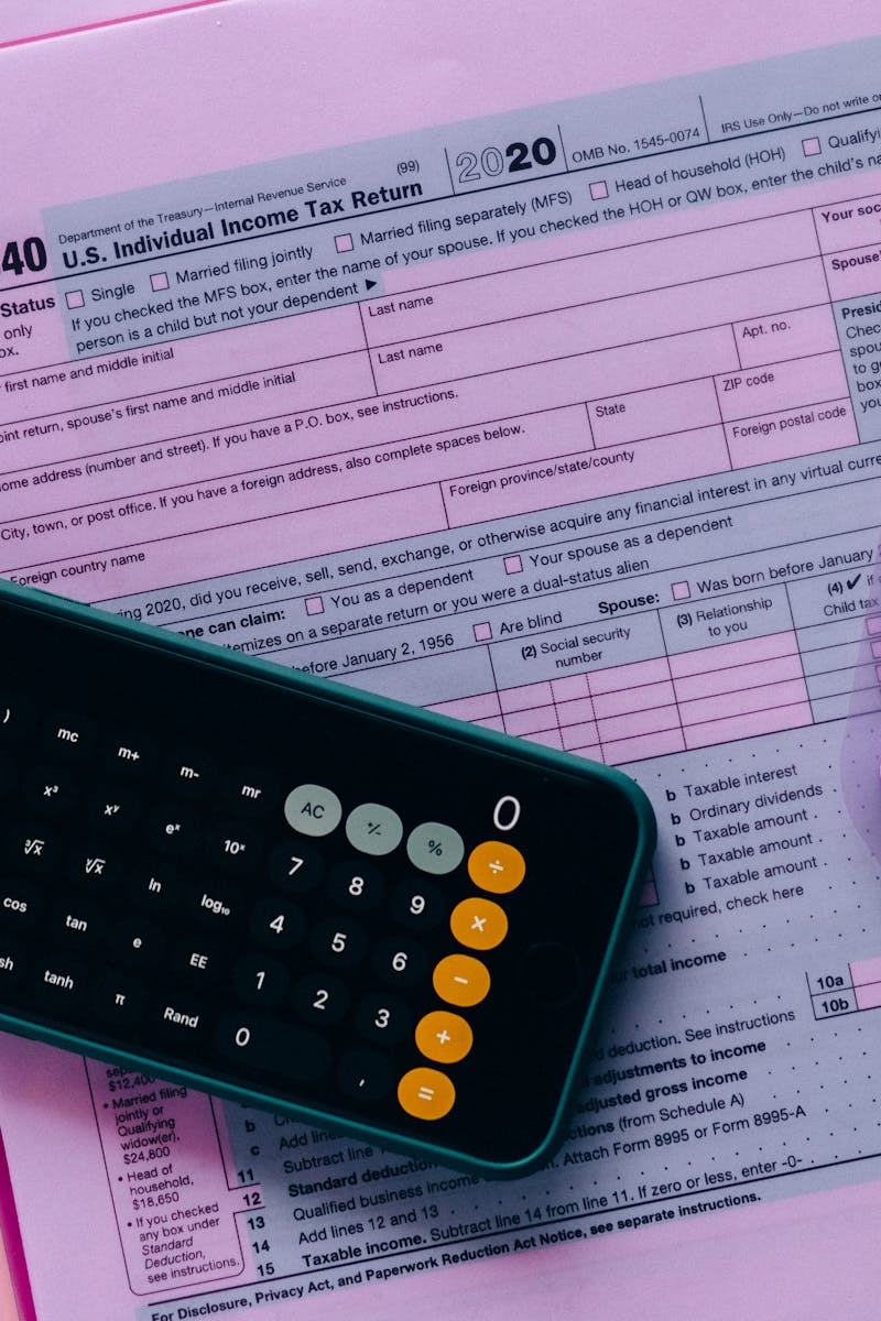 Tax form 1040 with a calculator on a pink background, highlighting finance and accounting themes.