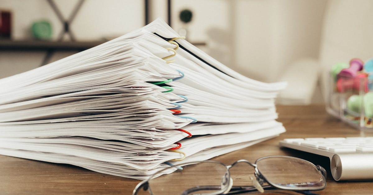 Close-up of a stack of office papers on a desk with glasses, emphasizing organization.