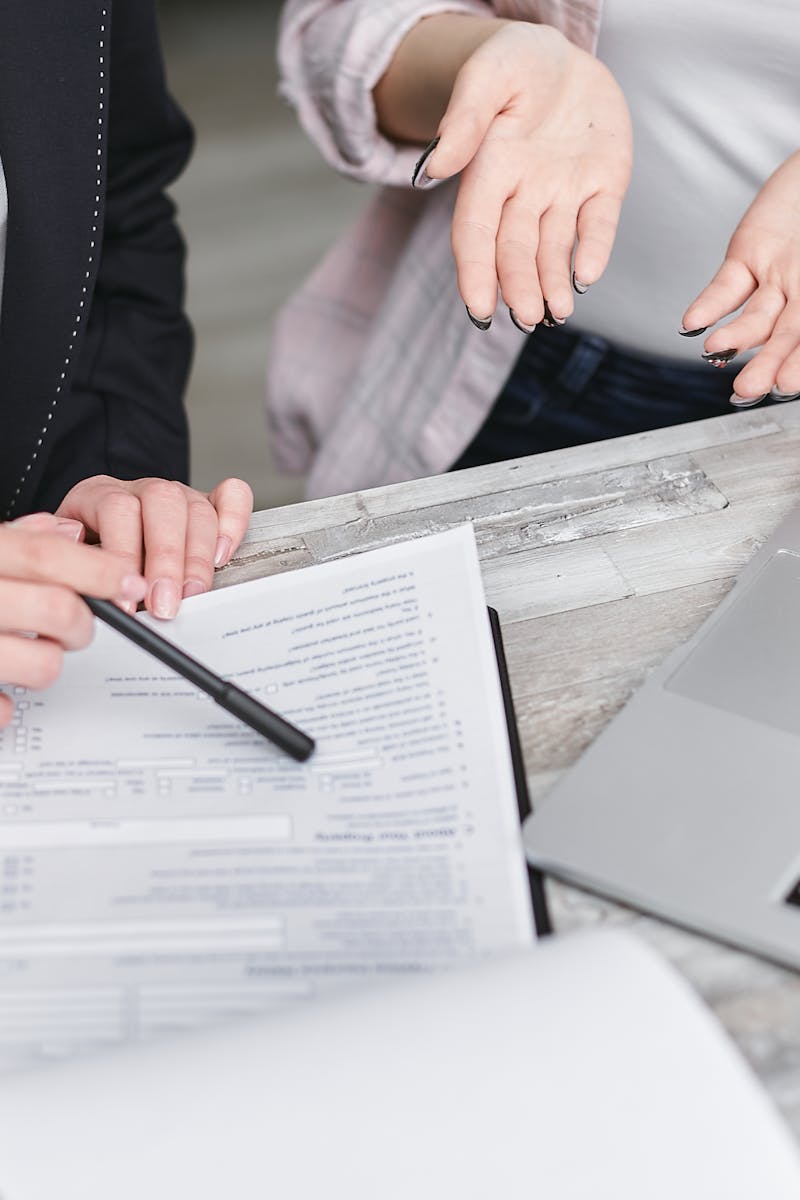 Two professionals discussing a contract at a business meeting with documents and a laptop.