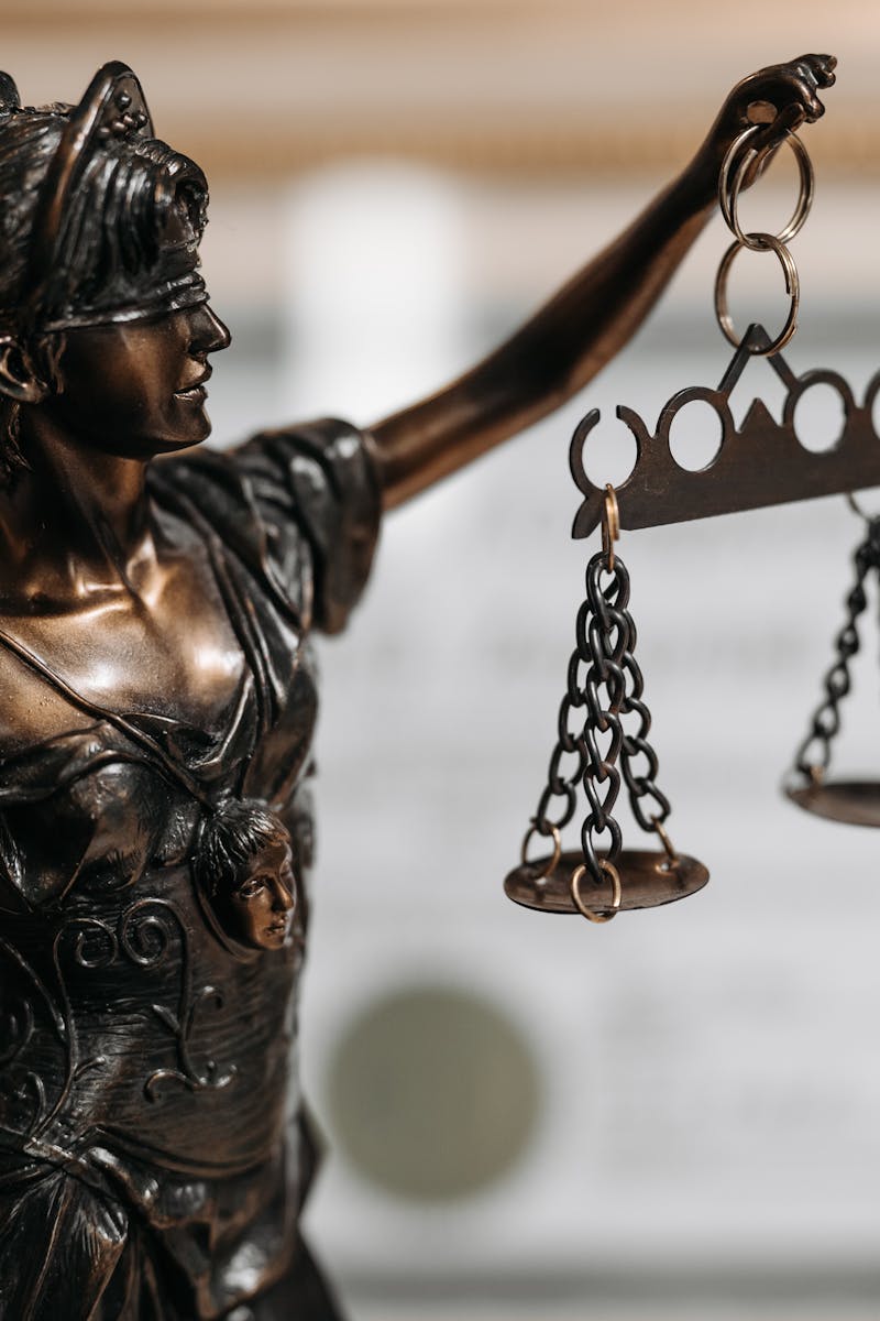 Close-up of a bronze Lady Justice statue holding scales in an office environment.